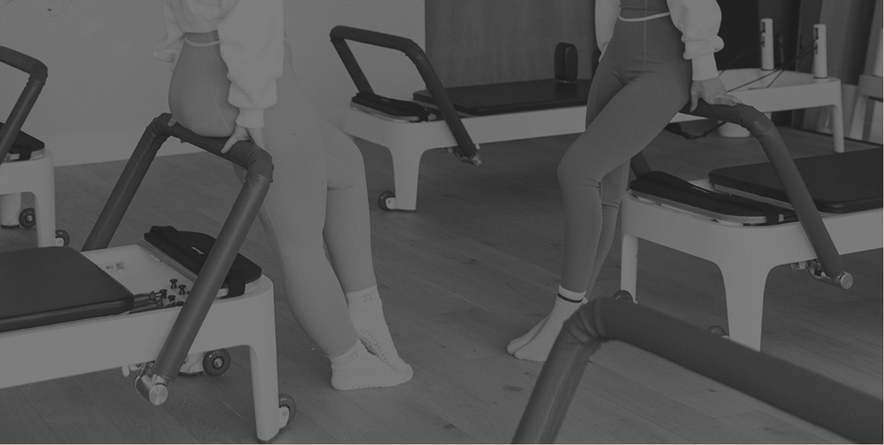 Black and white image of co-founders of a Pilates sock company hanging out in a Pilates studio.