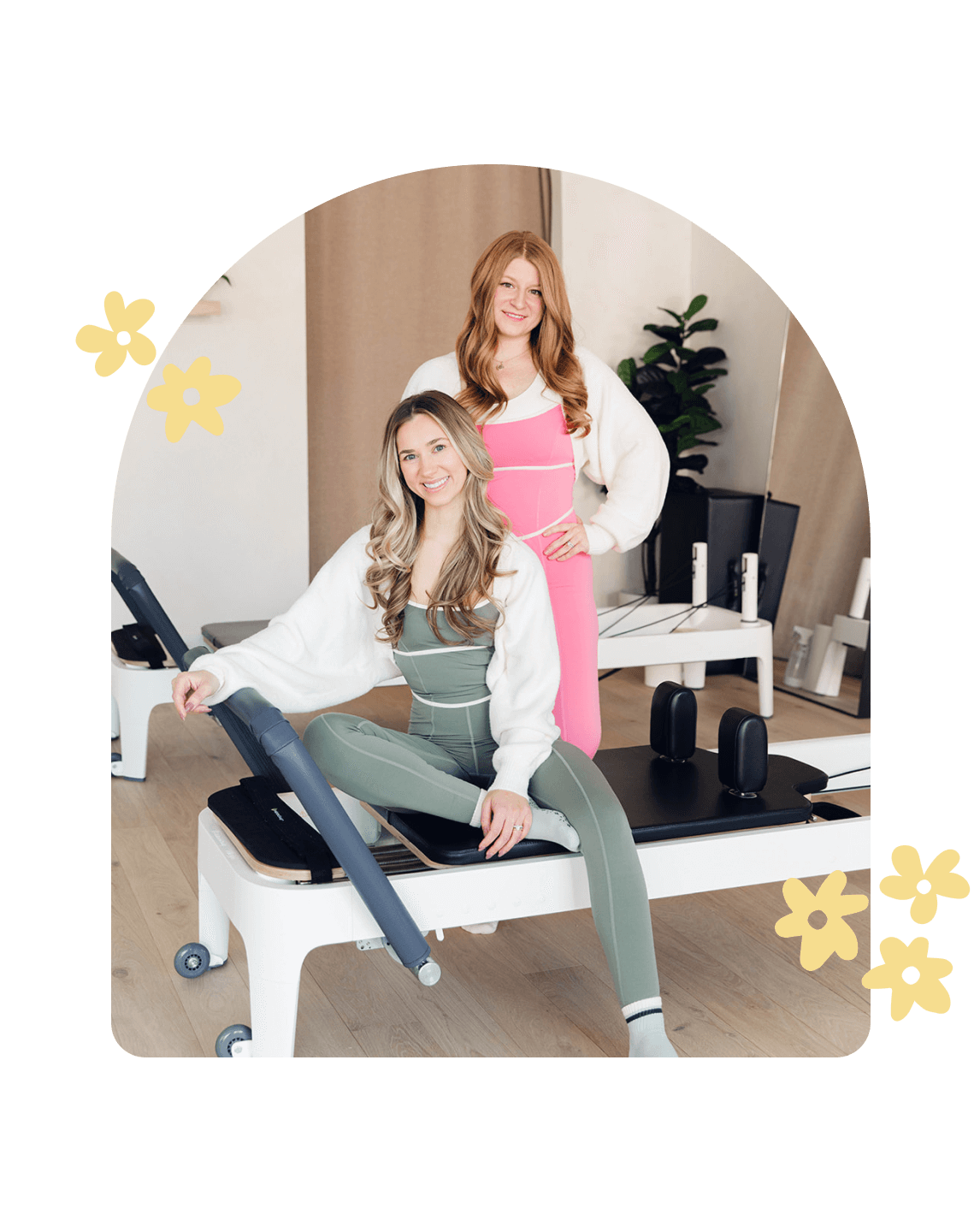 Co-founders of a Pilates sock company based in Chicago sitting on a Pilates reformer in matching workout sets.